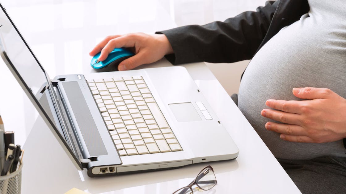 Zwangere medewerkster achter laptop