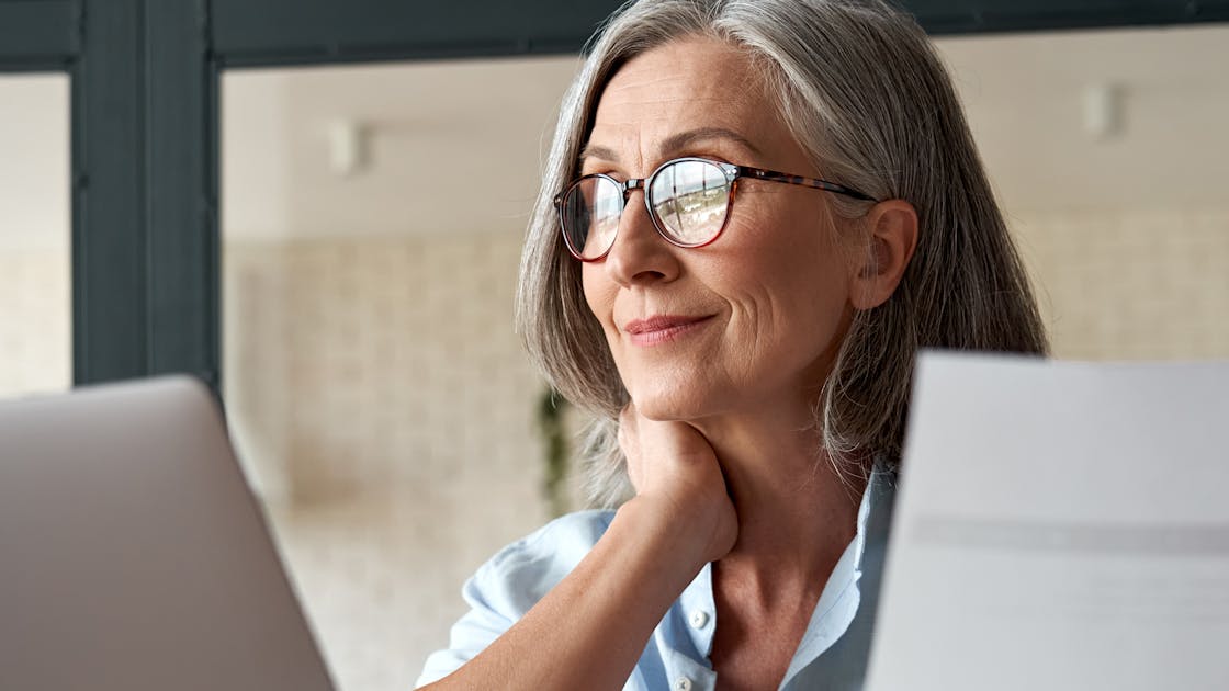 Vrouw met grijs haar en bril kijkt naar een scherm - inzetbaarheid ouderen 