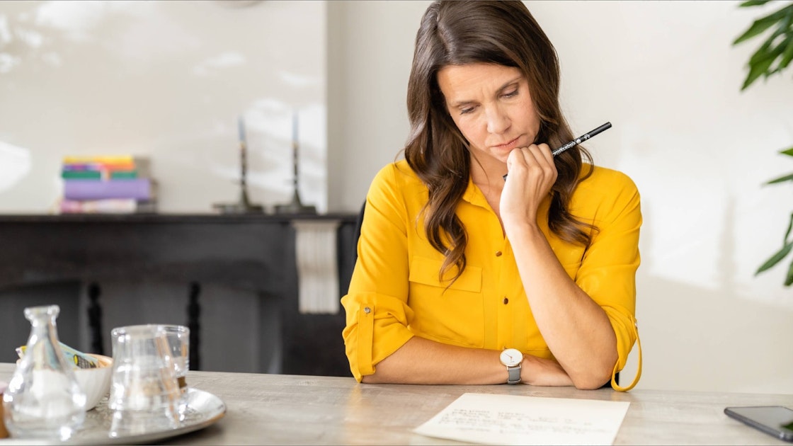 Vrouw in gele blouse leest heel aandachtig de juridische begrippen bij onbetaalde facturen