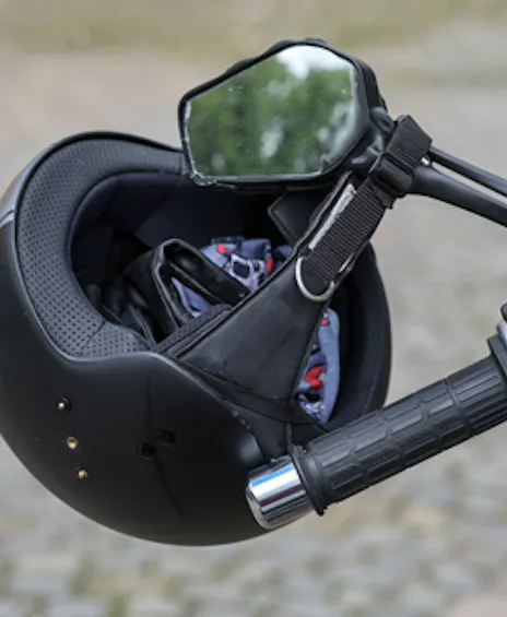 Helm voor brommer hangt aan stuur.