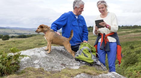Ouder echtpaar staat met hond in natuurgebied
