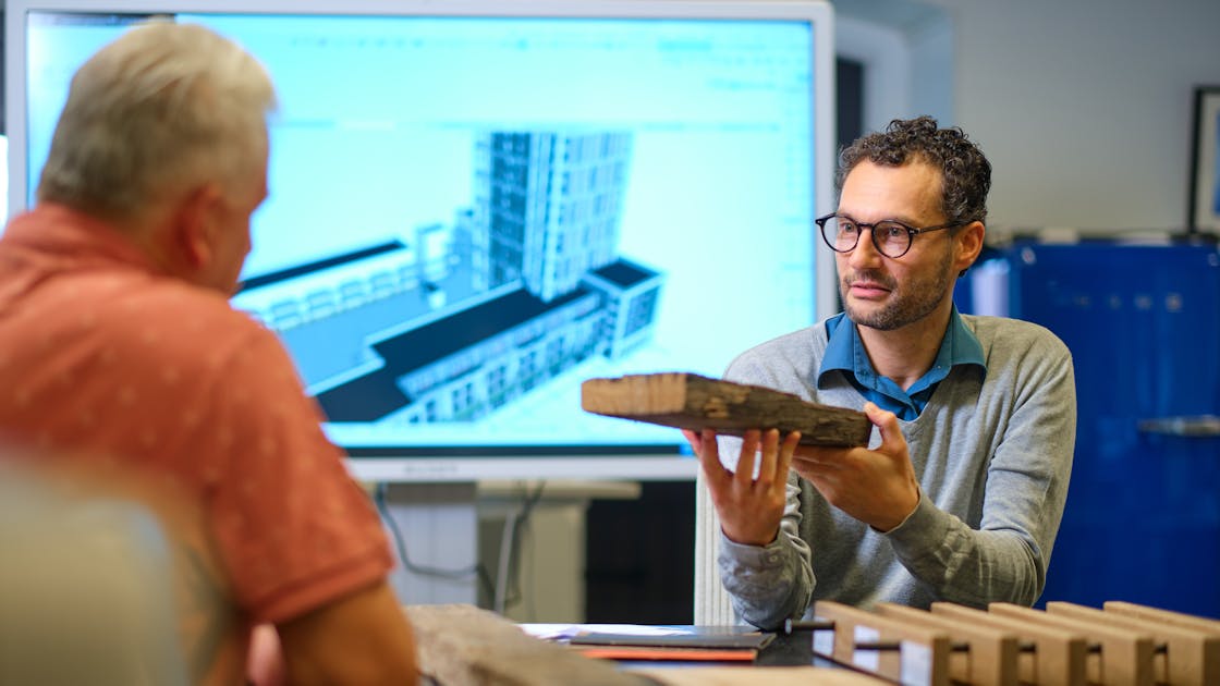 twee mannen aan tafel praten over architectuur