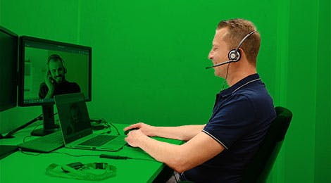 Man met headset op zit achter een laptop
